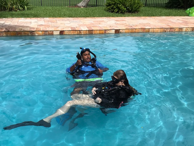 Parent and child learning to scuba dive together during a pool training session
