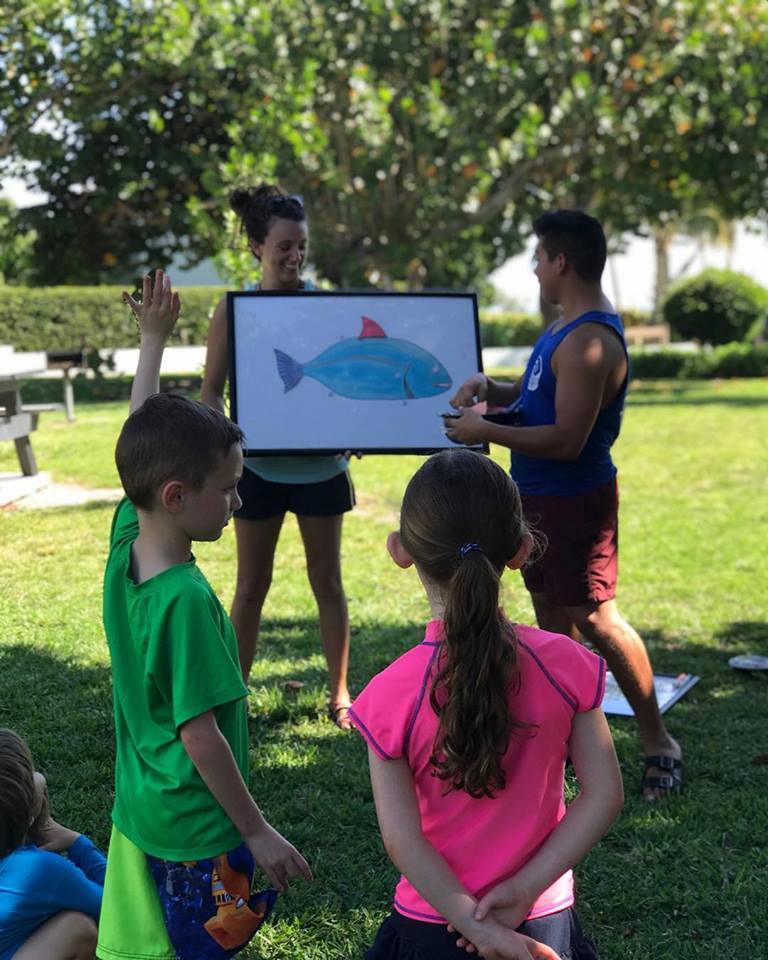 Marine biologist teaching fish identification to kids on an outdoor field trip