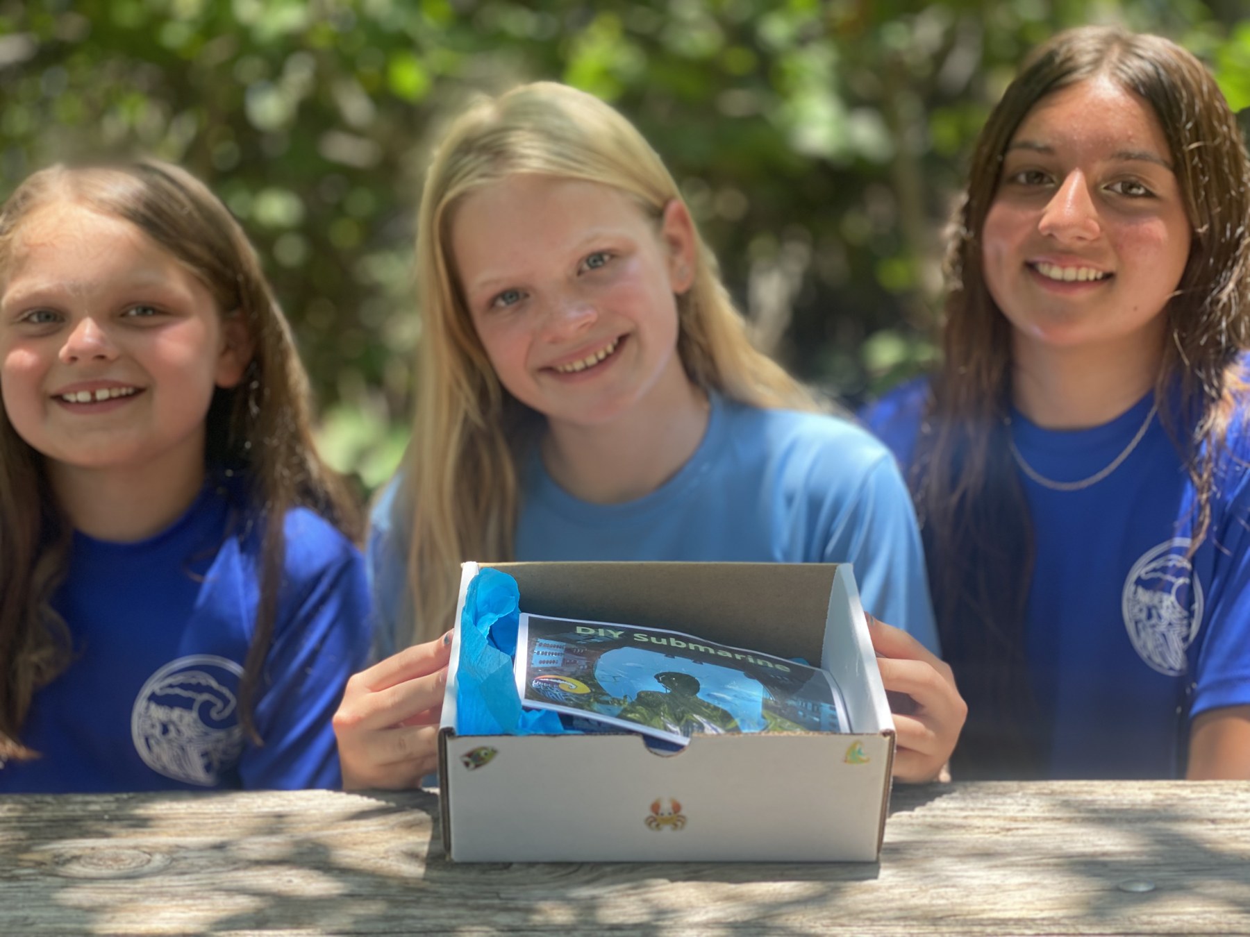 Three campers opening a Jr. Marine Biologist adventure kit