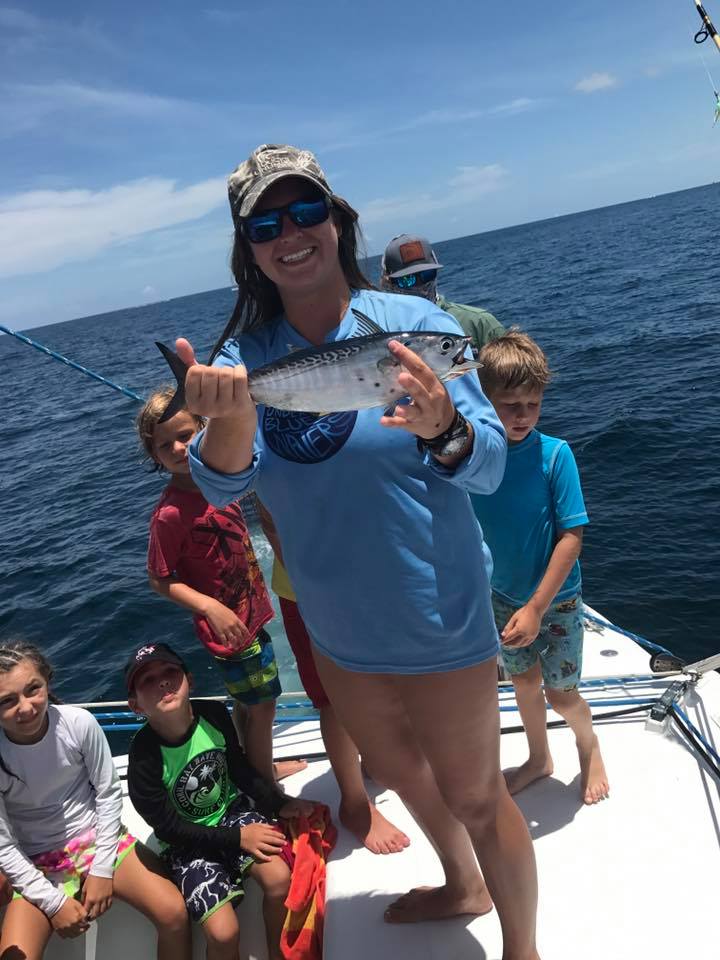 Instructor in an Under Blue Waters shirt showing campers a freshly caught fish on the boat